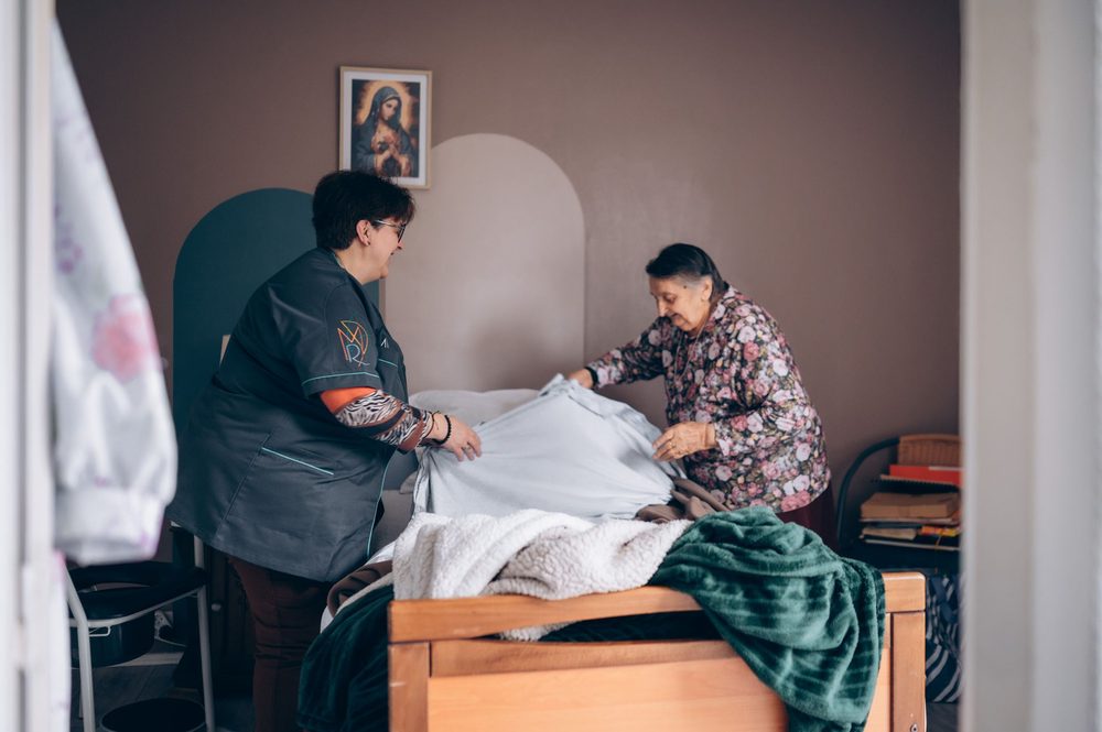 Une aide à domicile ADMR et une bénéficiaire refont un lit ensemble